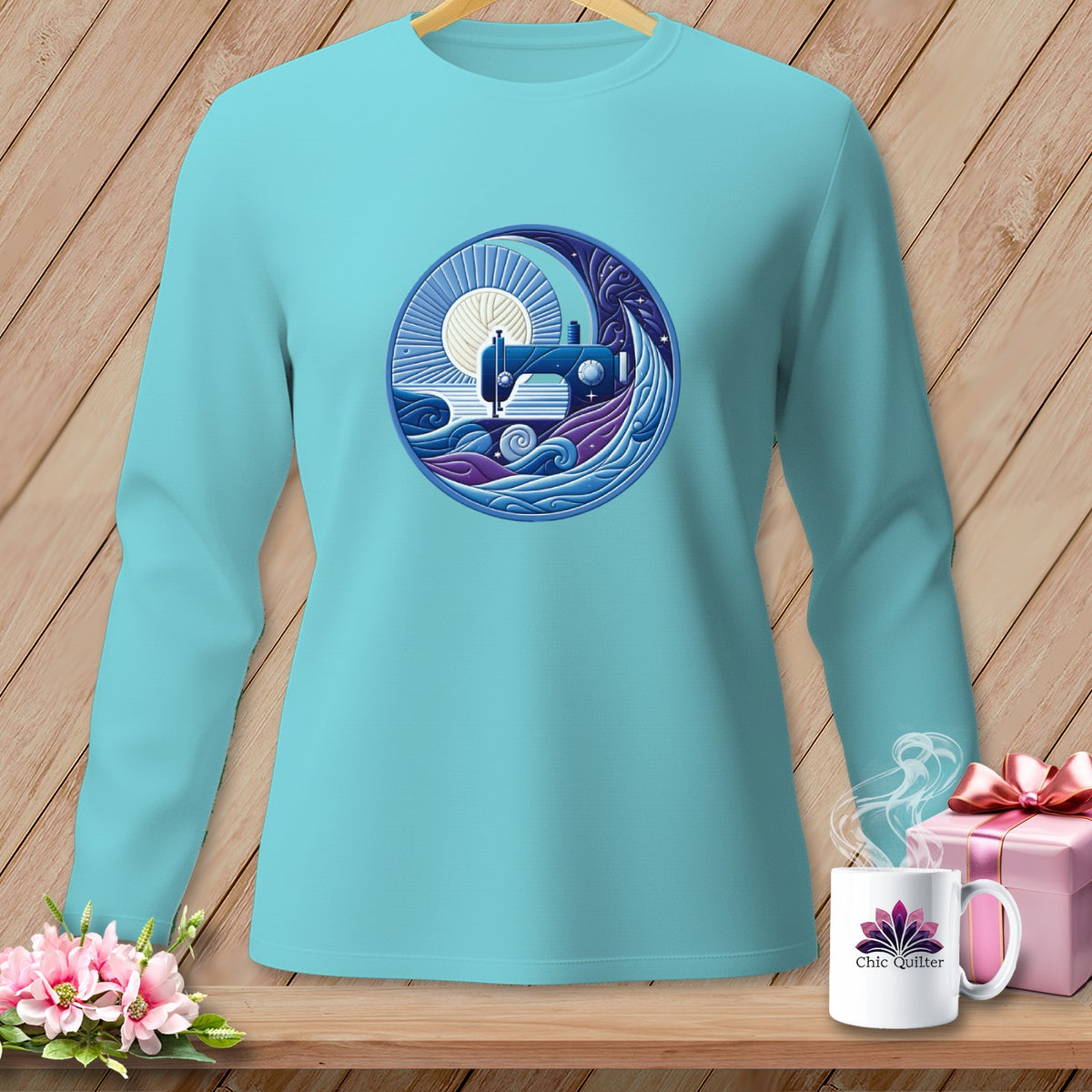 Turquoise long-sleeve shirt with a circular graphic of a sewing machine under a sun and waves.