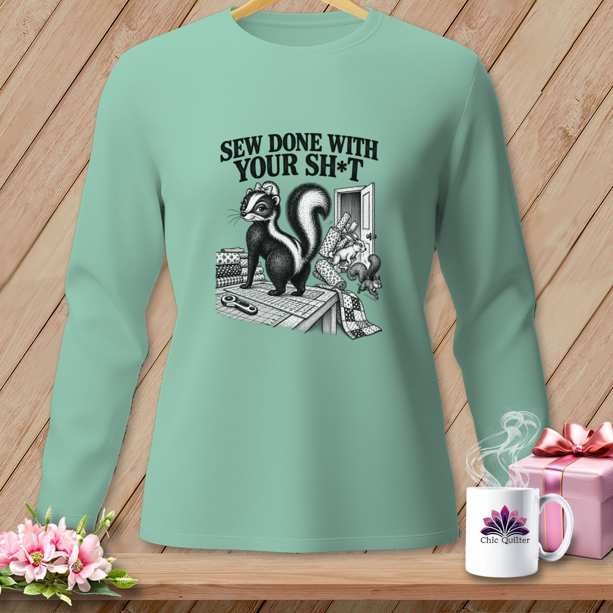 Mint green long-sleeve shirt with a skunk sewing graphic and text "SEW DONE WITH YOUR SH*T".