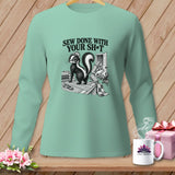 Mint green long-sleeve shirt with a skunk sewing graphic and text 