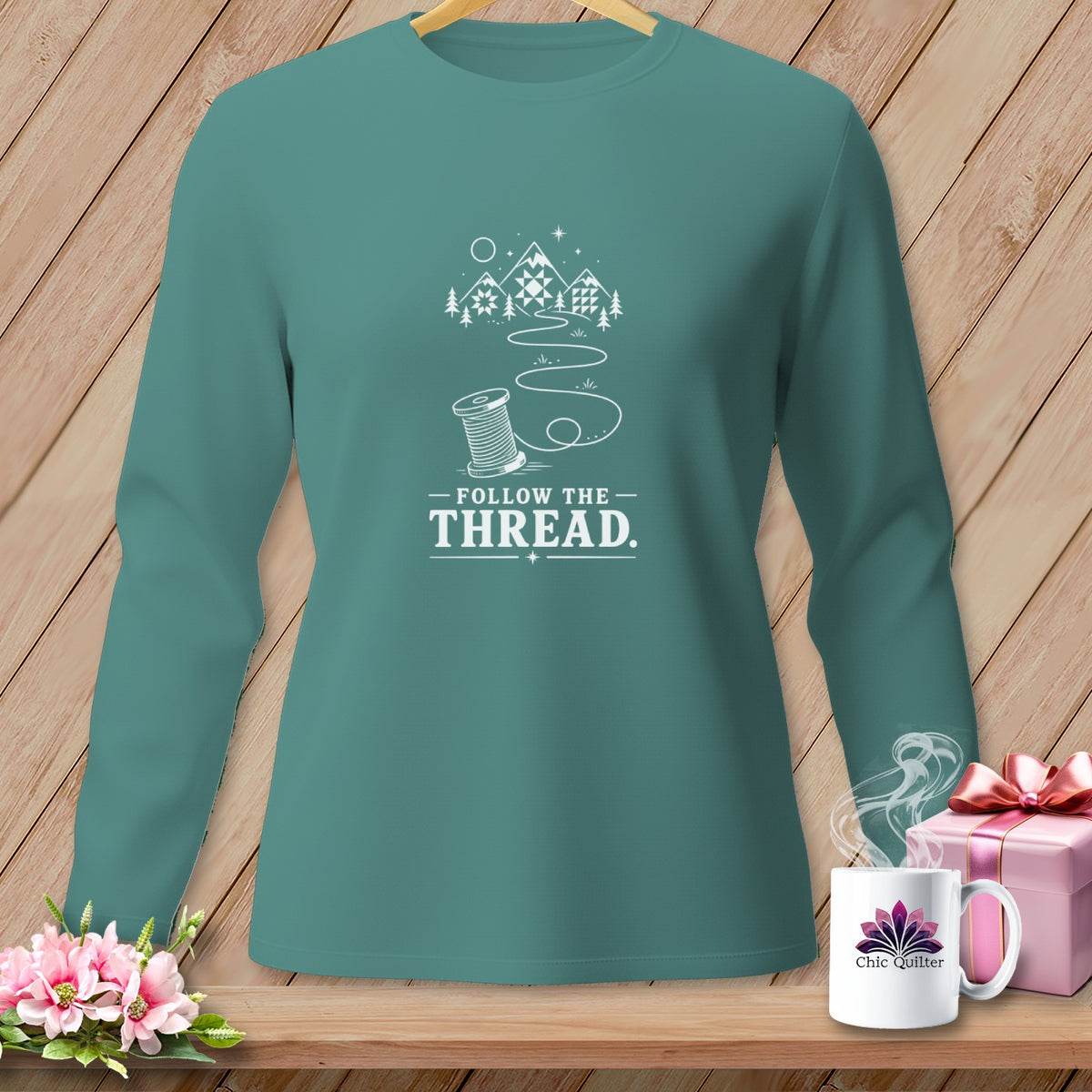 Teal long-sleeve shirt with "Follow the Thread" text and sewing graphics.