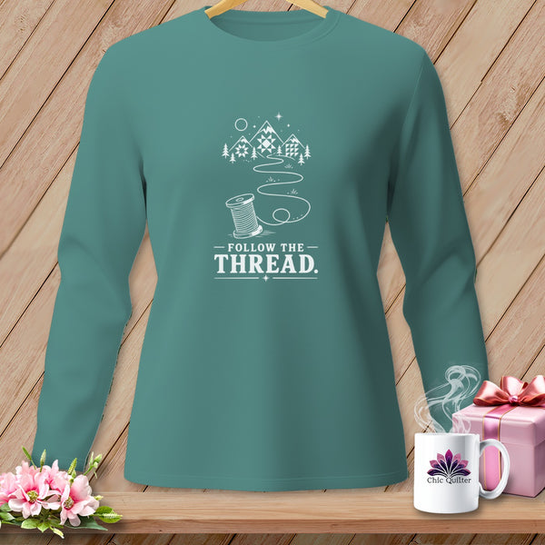Teal long-sleeve shirt with "Follow the Thread" text and sewing graphics.