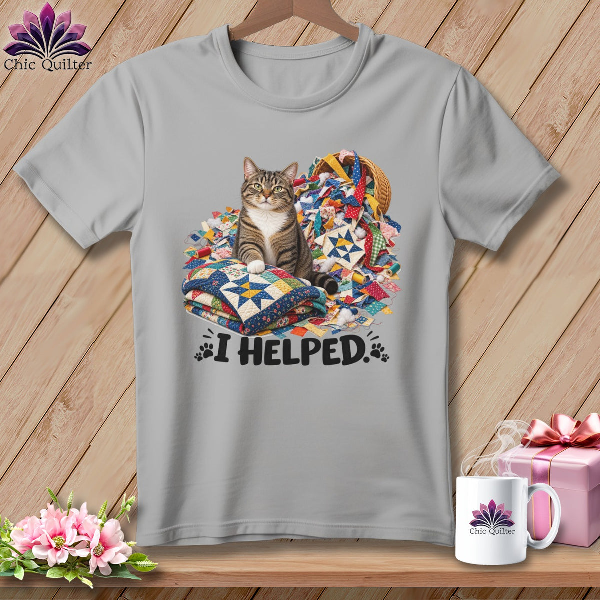 Tabby cat sits on quilts surrounded by fabric scraps and text "I HELPED."