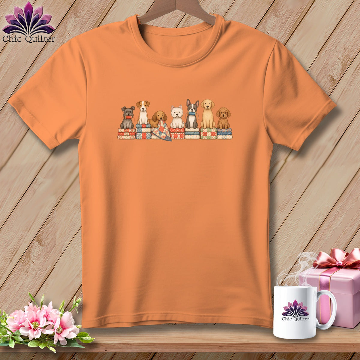 Orange t-shirt featuring a cartoon graphic of dogs sitting on folded quilts against a wooden background.