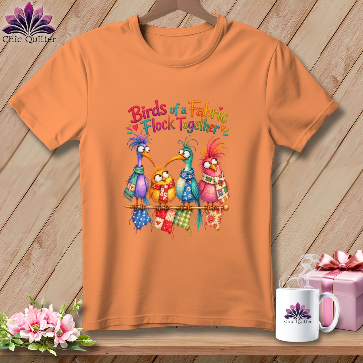 Orange t-shirt featuring four colorful cartoon birds wearing scarves, sitting together with quilt blocks.