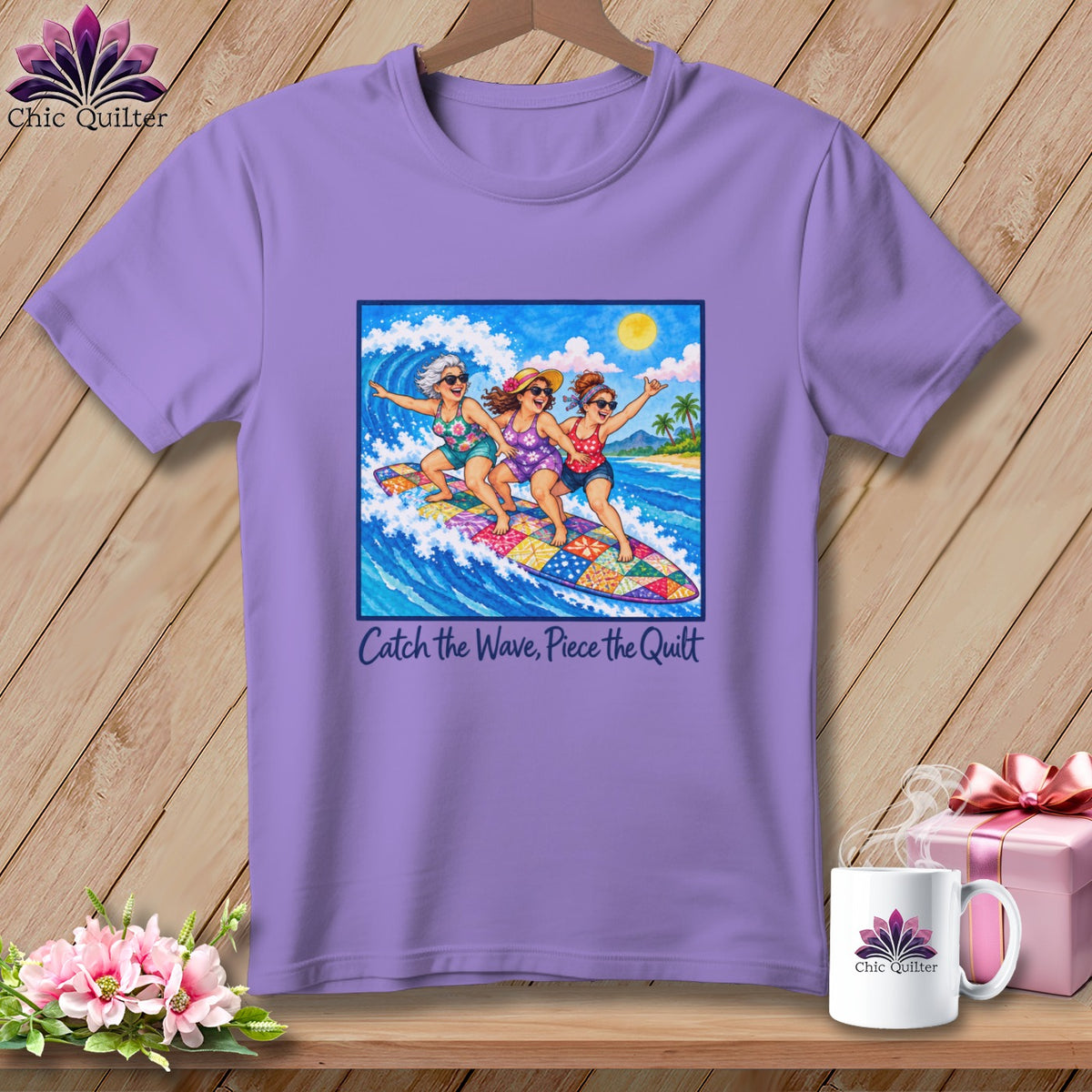 A light purple t-shirt featuring a graphic of three women surfing on a colorful patchwork surfboard.