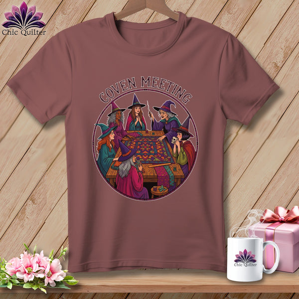 Witches around a table sewing a quilt with "Coven Meeting" text.