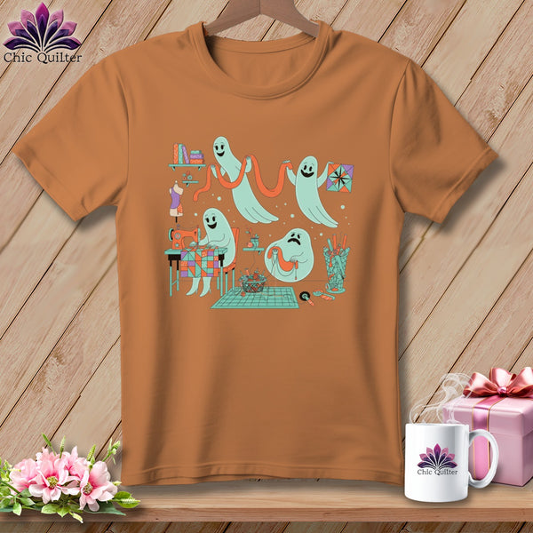 Orange t-shirt with ghosts sewing and quilting, holding a quilt square.