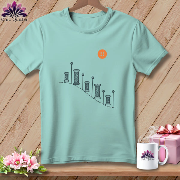 Aqua t-shirt with sewing thread spools and button graphic.
