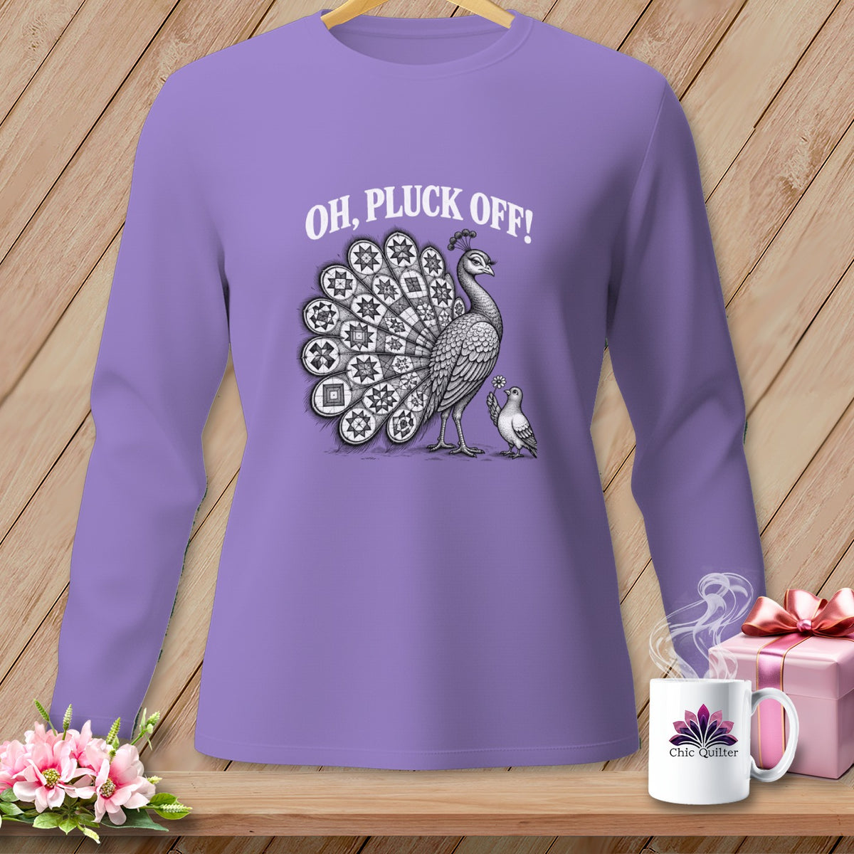 Purple long-sleeve t-shirt with a graphic of a peacock, a smaller bird, and the text "OH, PLUCK OFF!" displayed against a wooden background.