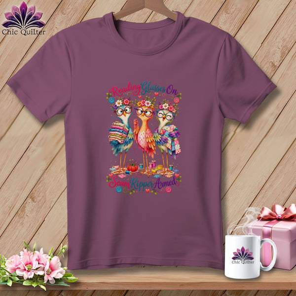 Plum crewneck t-shirt featuring a graphic of three colorful birds wearing glasses and flower crowns with the text Reading Glasses On Seam Ripper Armed.