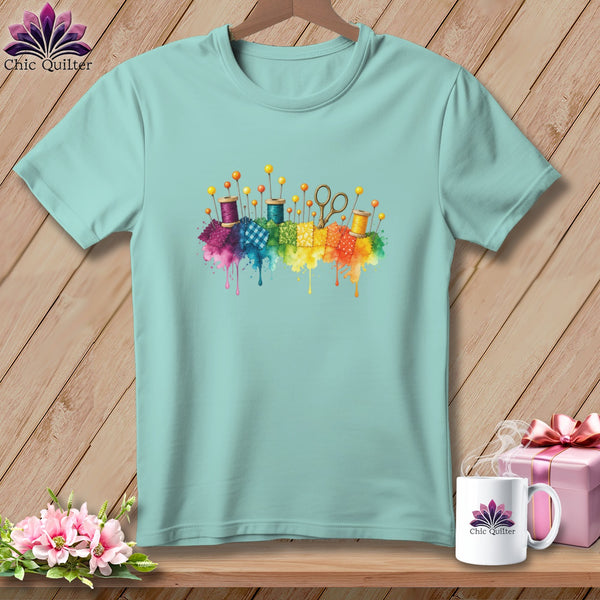 Light blue t-shirt with watercolor sewing supplies and patchwork blocks.