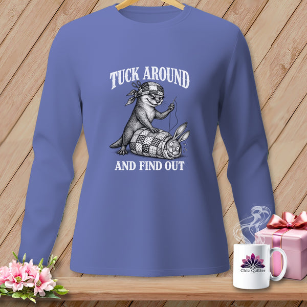 Periwinkle long-sleeve t-shirt with a humorous graphic of an otter sewing up a rolled-up rabbit, featuring the text Tuck Around and Find Out.
