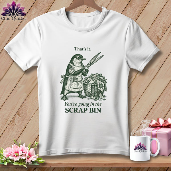 Penguin wearing apron holding scissors, with basket of quilt scraps. Text reads "That's it. You're going in the SCRAP BIN."