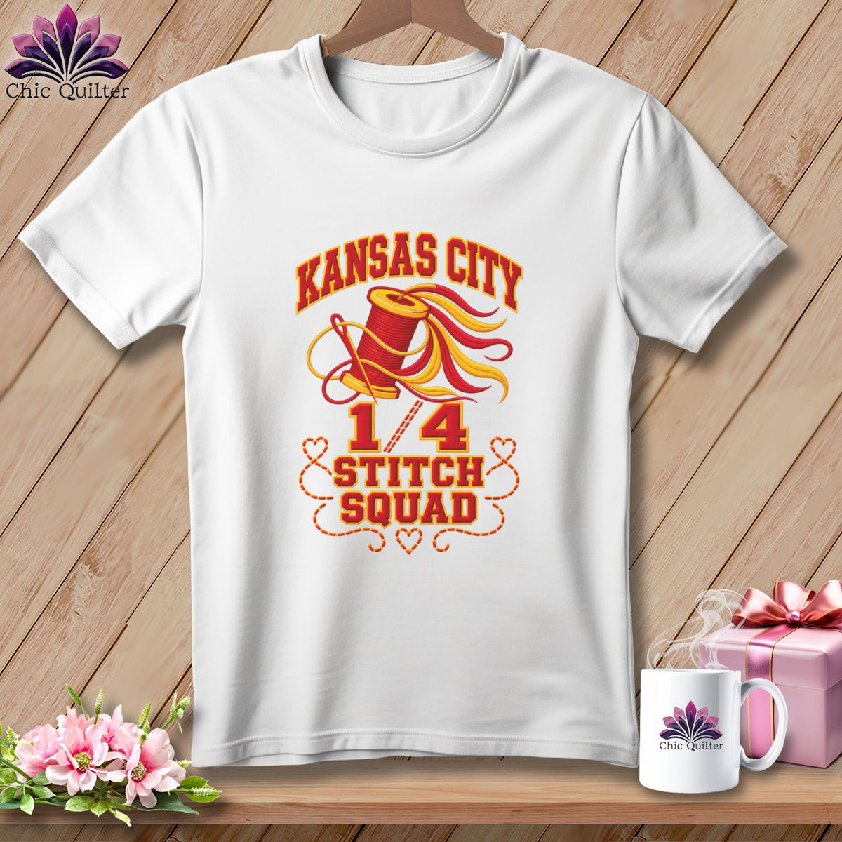 A white t-shirt on a wooden background with a graphic featuring a spool of thread and the text "Kansas City 1/4 Stitch Squad".