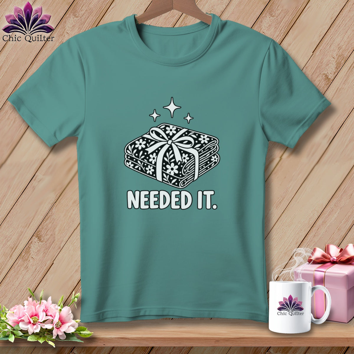 Teal t-shirt with a graphic of fabric bundle and the text "NEEDED IT."