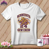 A white t-shirt features a graphic with a cartoon Viking holding a needle, the text Minnesota Sew Crew 24, and matching mug and gift box on wood.