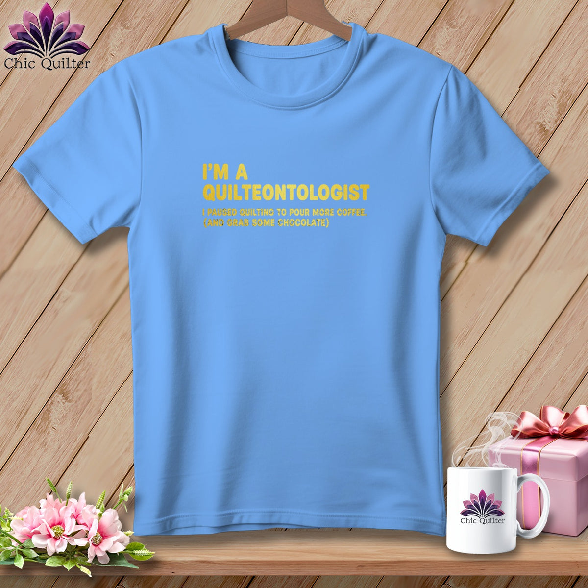 Light blue t-shirt with yellow text "I'M A QUILTEONTOLOGIST (PAUSED QUILTING TO POUR MORE COFFEE. (AND GRAB SOME CHOCOLATE))".