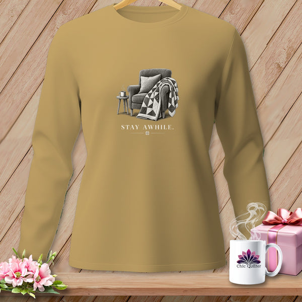 Long sleeve shirt with "STAY AWHILE." graphic of armchair, quilt, and tea.