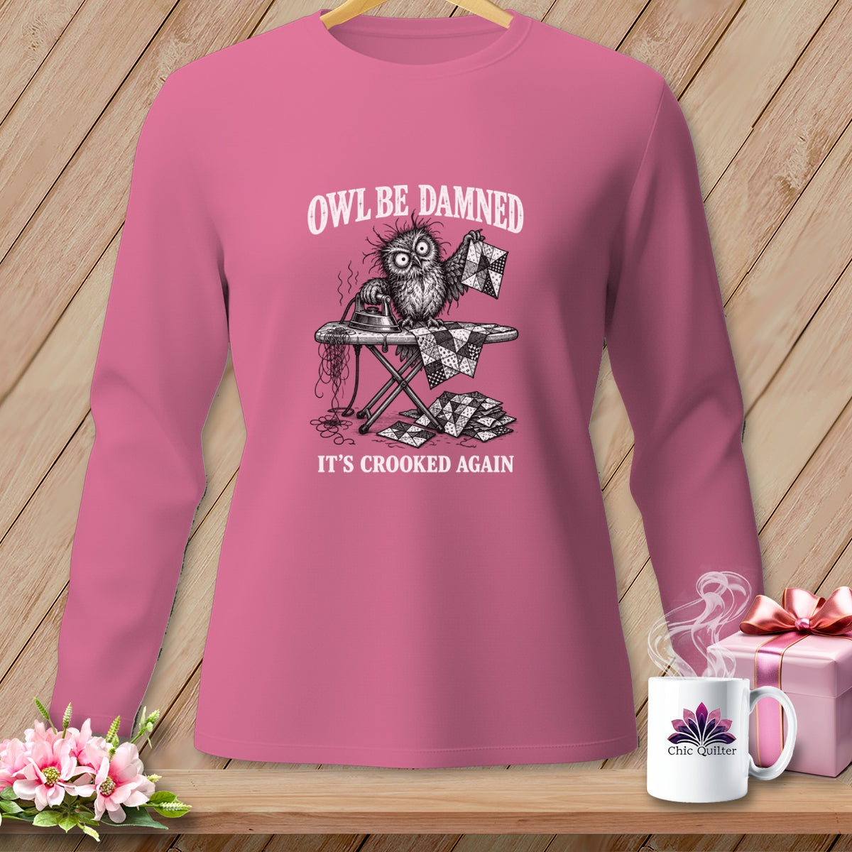 Long sleeve shirt with a cartoon owl ironing a crooked quilt, text "Owl Be Damned, It's Crooked Again".