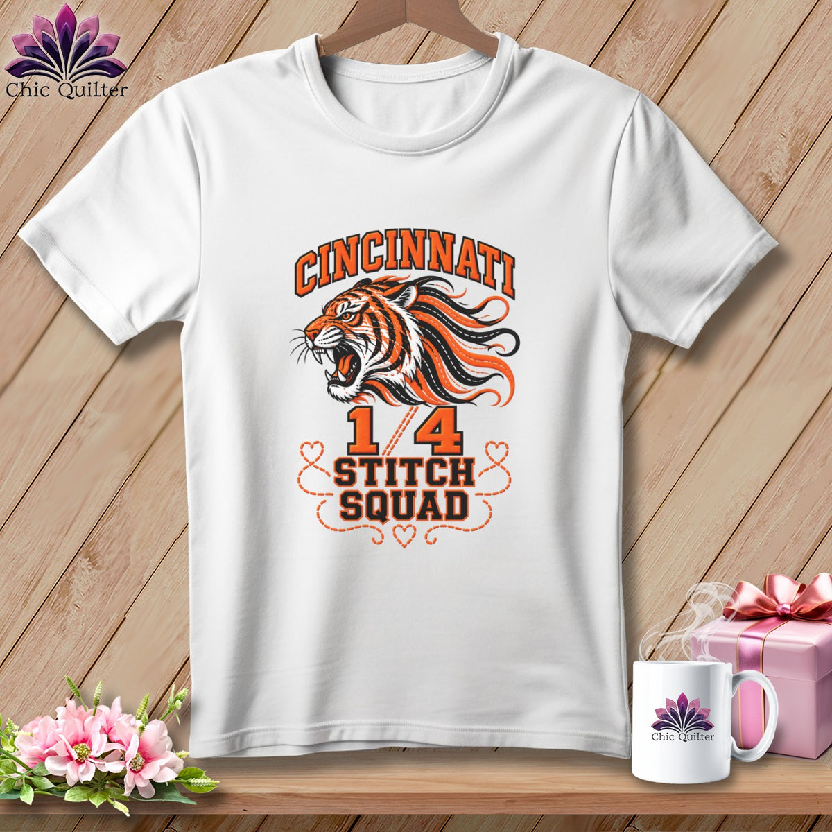 A white t-shirt hanging on a wooden background, featuring a Cincinnati tiger graphic and the text 1/4 Stitch Squad.