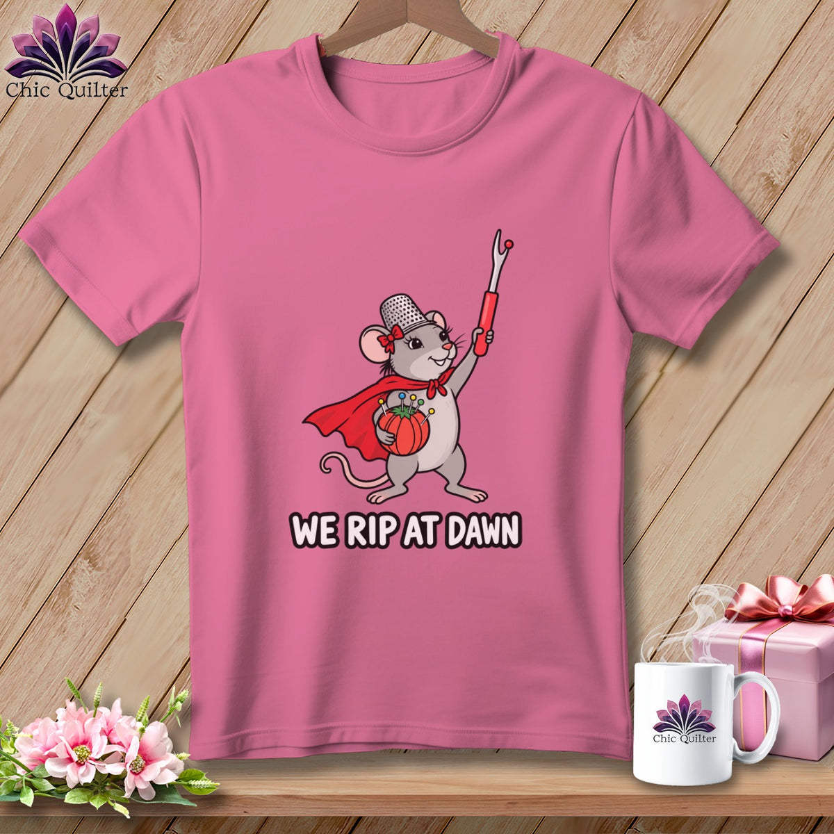 A pink t-shirt displays a graphic of a mouse holding a seam ripper with the text WE RIP AT DAWN.