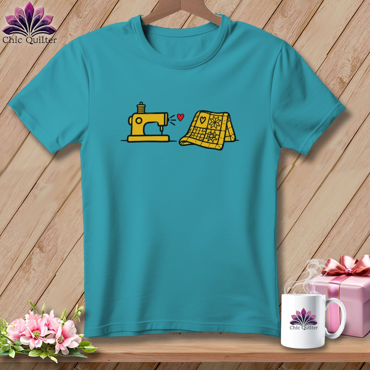Teal short-sleeve t-shirt featuring a yellow sewing machine and quilt graphic with a small red heart.