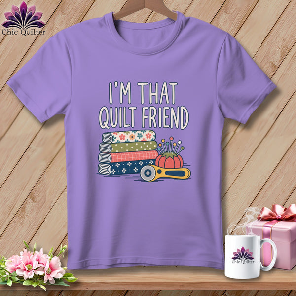 A purple crewneck t-shirt featuring the text I'm That Quilt Friend, stacked fabric, a pincushion, and a rotary cutter.