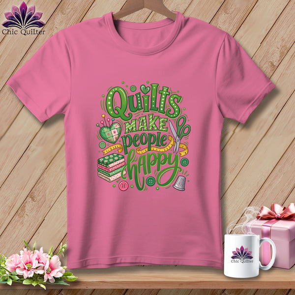 Pink t-shirt with green graphic text that reads Quilts Make People Happy, surrounded by sewing-themed illustrations.
