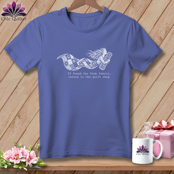 Periwinkle t-shirt with white graphic of a woman flying with a quilt and text.