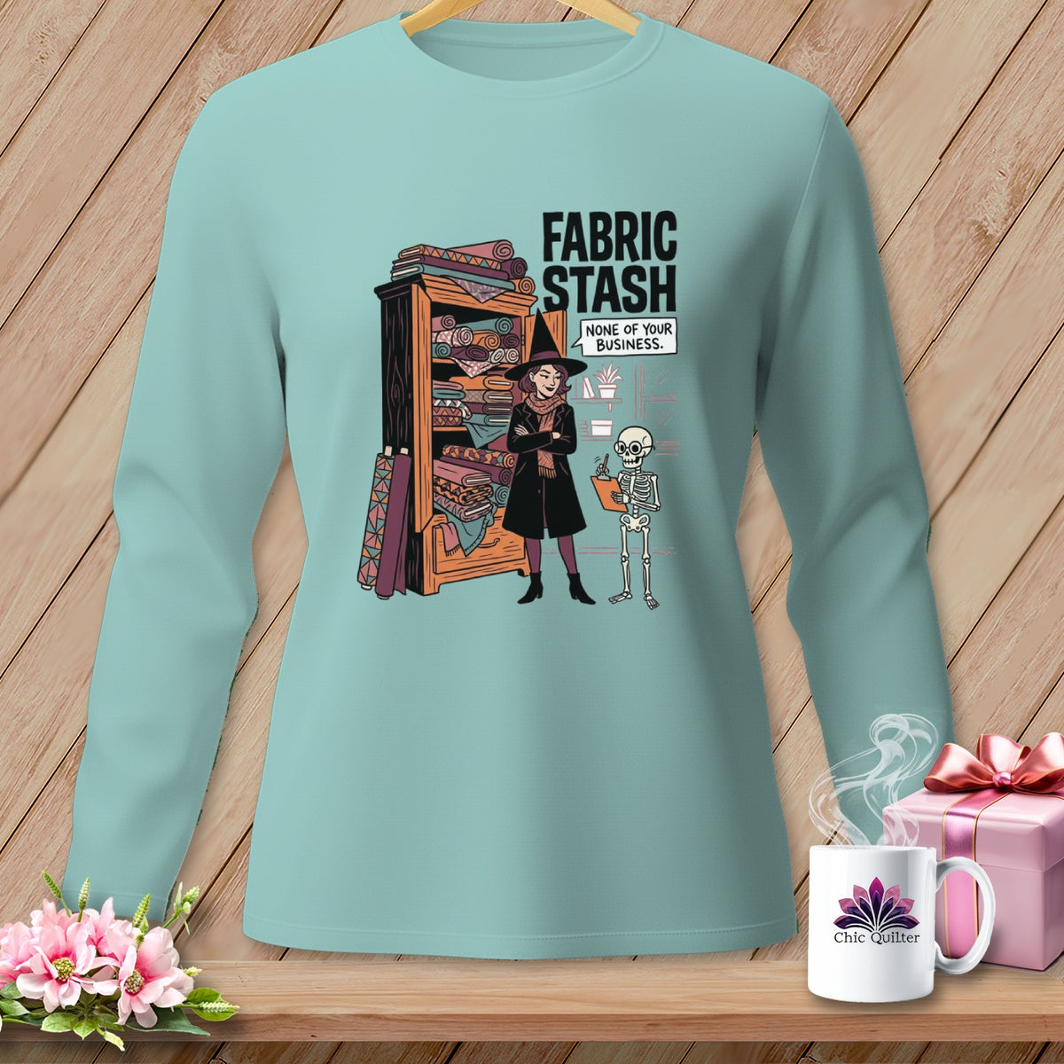Light blue long sleeve shirt with "Fabric Stash" text and a witch with a skeleton.