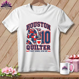 White t-shirt with a graphic of a folded quilt, a coffee mug, and text reading Houston Quilter.