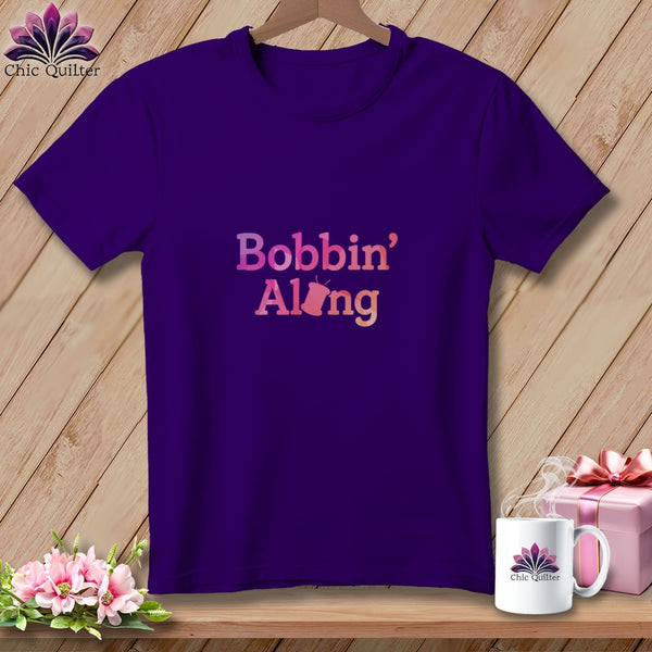 Purple t-shirt with "Bobbin' Along" text and sewing machine graphic.