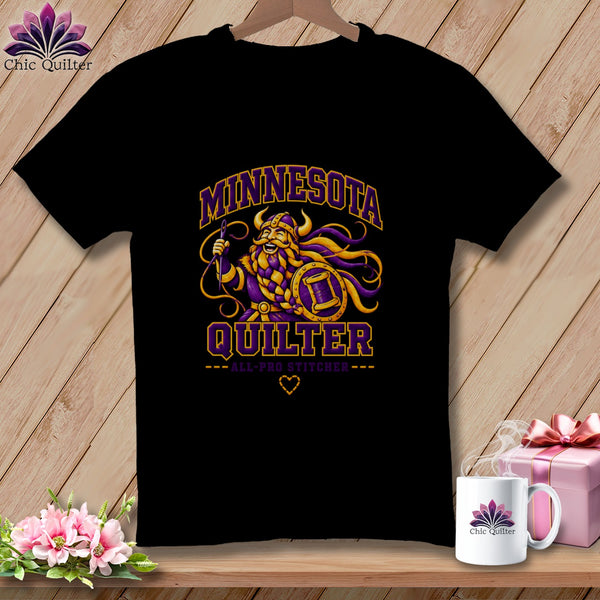 Black t-shirt featuring a Viking graphic with "Minnesota Quilter" text and a matching mug on a wooden background.