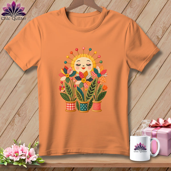 An orange t-shirt displays a graphic of a smiling sun and colorful fabric flowerpots.
