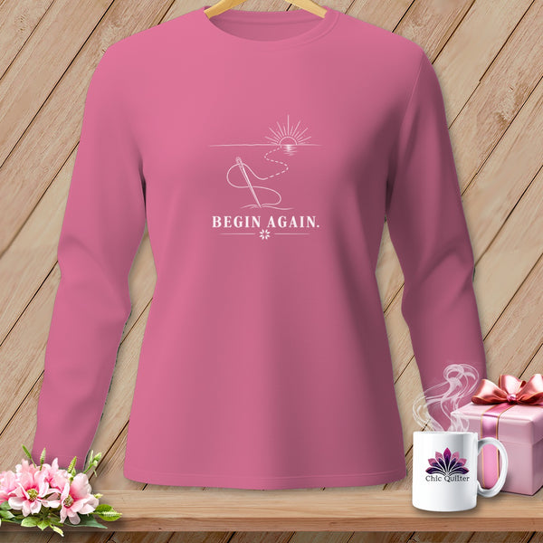 Pink long-sleeve shirt with "BEGIN AGAIN." and needle and thread design.