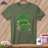 An olive green t-shirt with green text reading Quilts Make People Happy surrounded by sewing motifs.