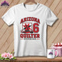 A white t-shirt hanging on a wooden background, featuring a red and black Arizona Quilter Stitch Six graphic.