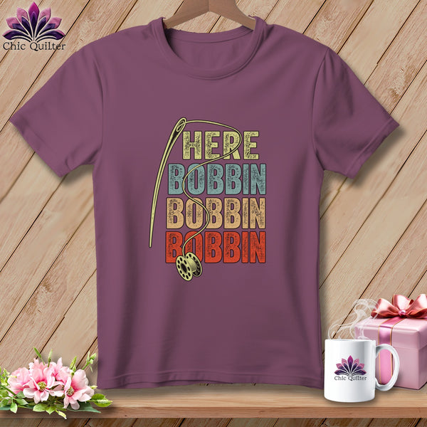 Purple t-shirt with "HERE BOBBIN" repeated in retro font and sewing needle.