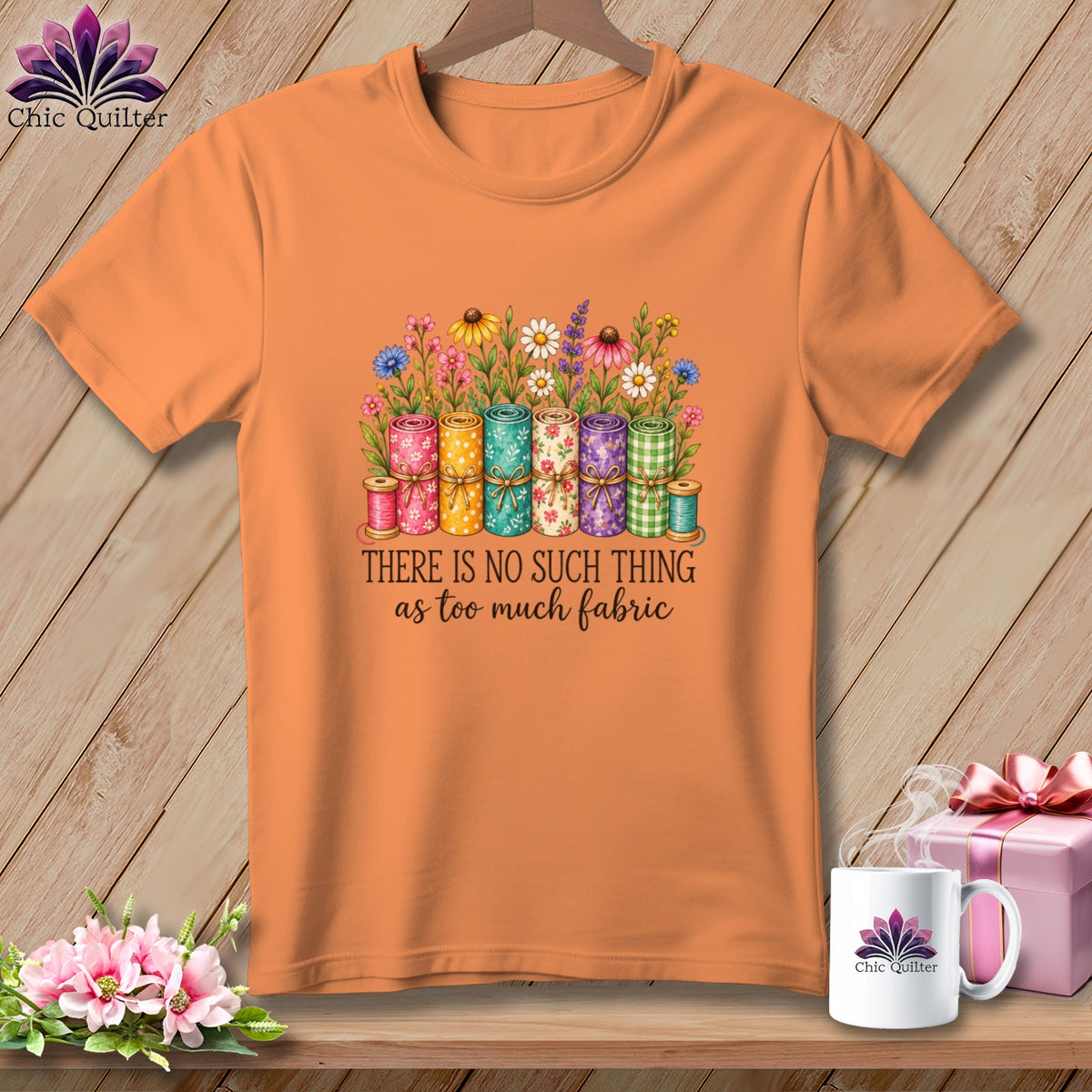 Orange t-shirt featuring rolled fabric graphic, floral illustration, and text reading There is no such thing as too much fabric.