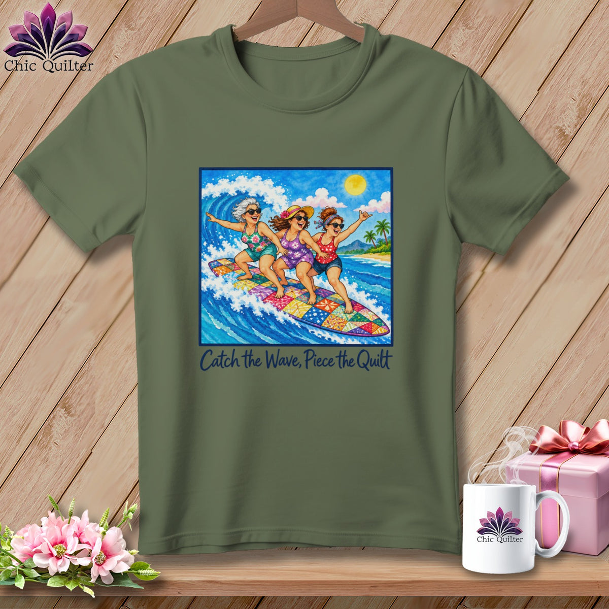 Olive green t-shirt with a graphic of three women surfing, with the text "Catch the Wave, Piece the Quilt."