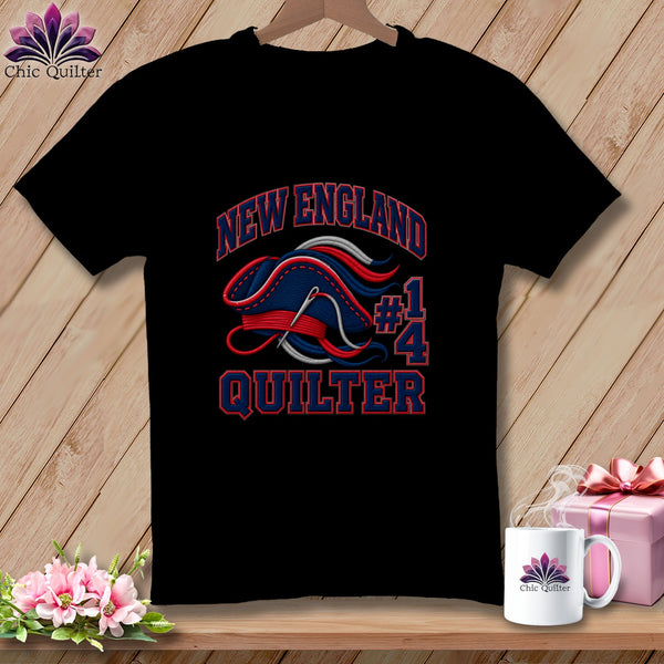 Black t-shirt featuring New England Quilter graphic with a needle and thread forming a hat.