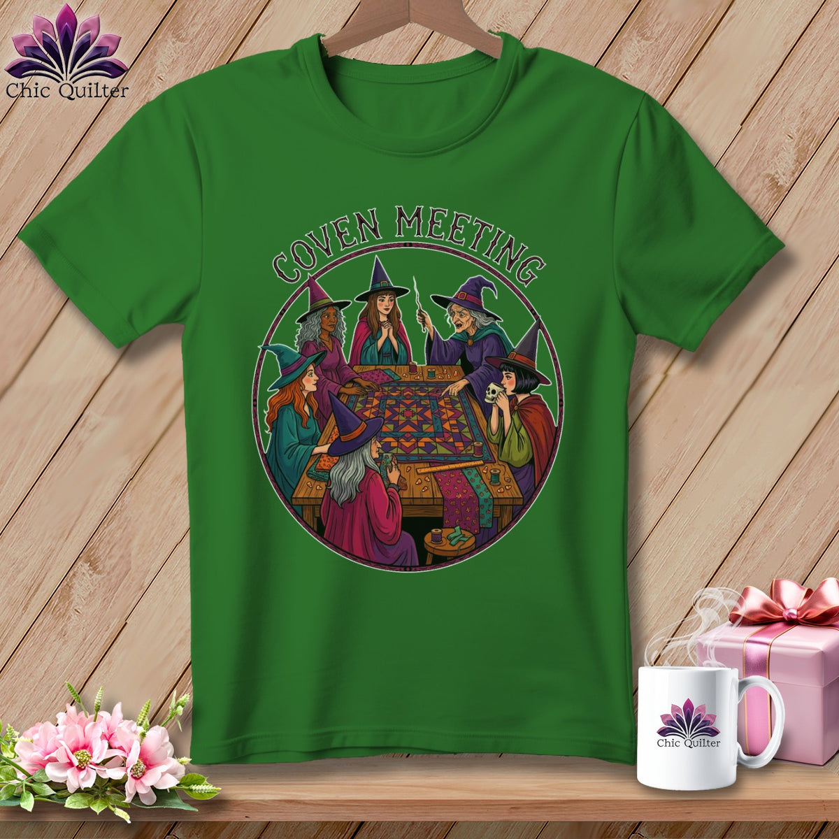 Green t-shirt with a circular illustration of witches having a coven meeting around a table.