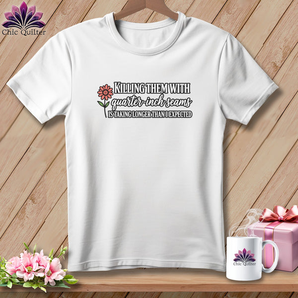 A white t-shirt hanging on a wooden background, featuring the text Killing them with quarter inch seams is taking longer than I expected.