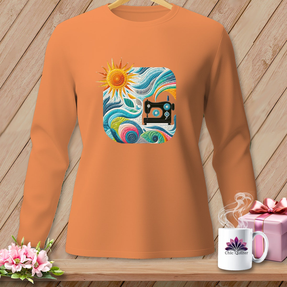 Orange long-sleeved shirt with a colorful square graphic of a sewing machine and sun.