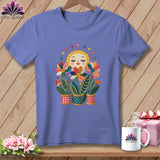 Blue crewneck t-shirt with a whimsical graphic of a smiling sun and flowers planted in spools of thread.