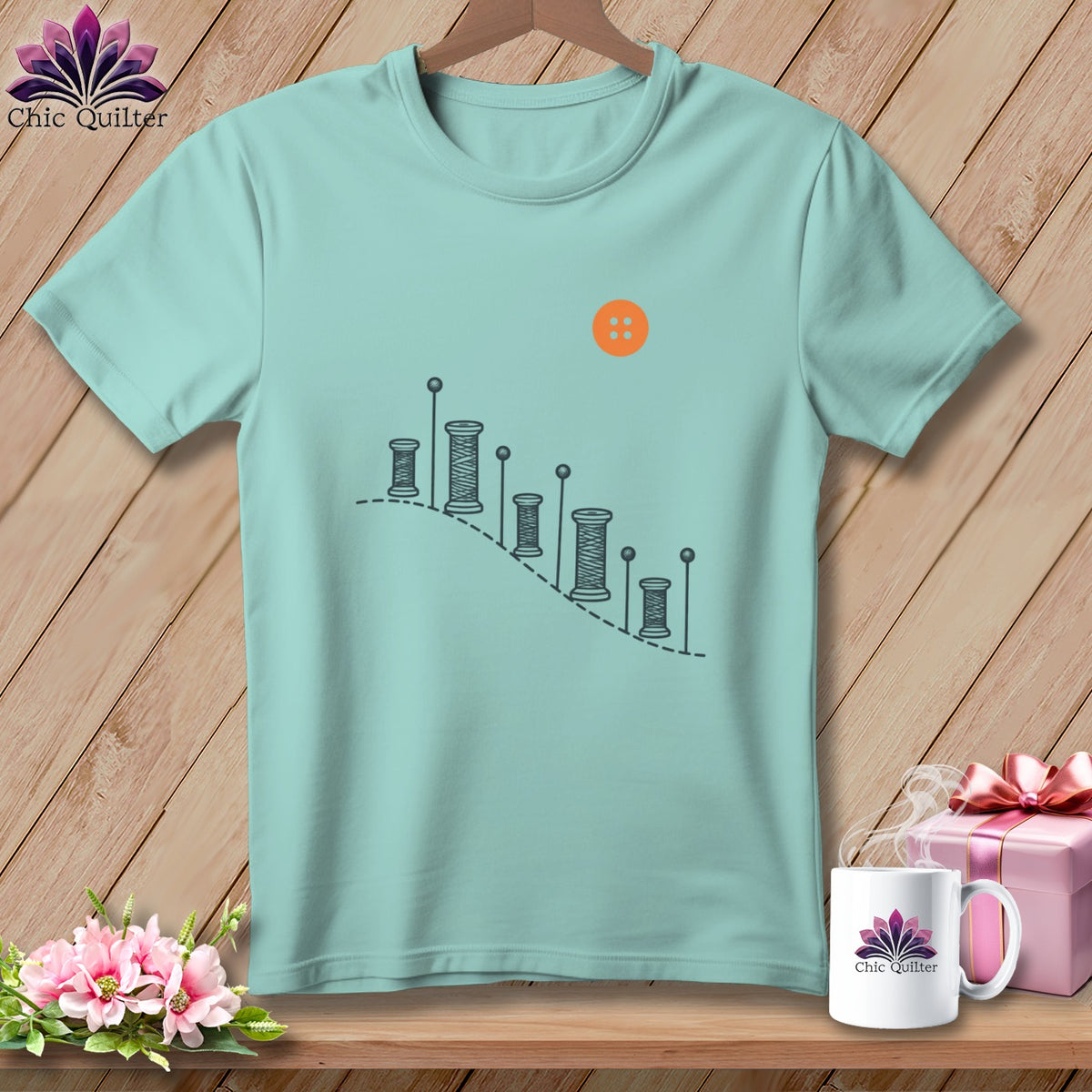 Light blue t-shirt with spools of thread graphic and orange button.