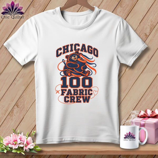 A white crewneck t-shirt features a navy and orange graphic of a bear holding a spool of thread with the text Chicago 100 Fabric Crew.