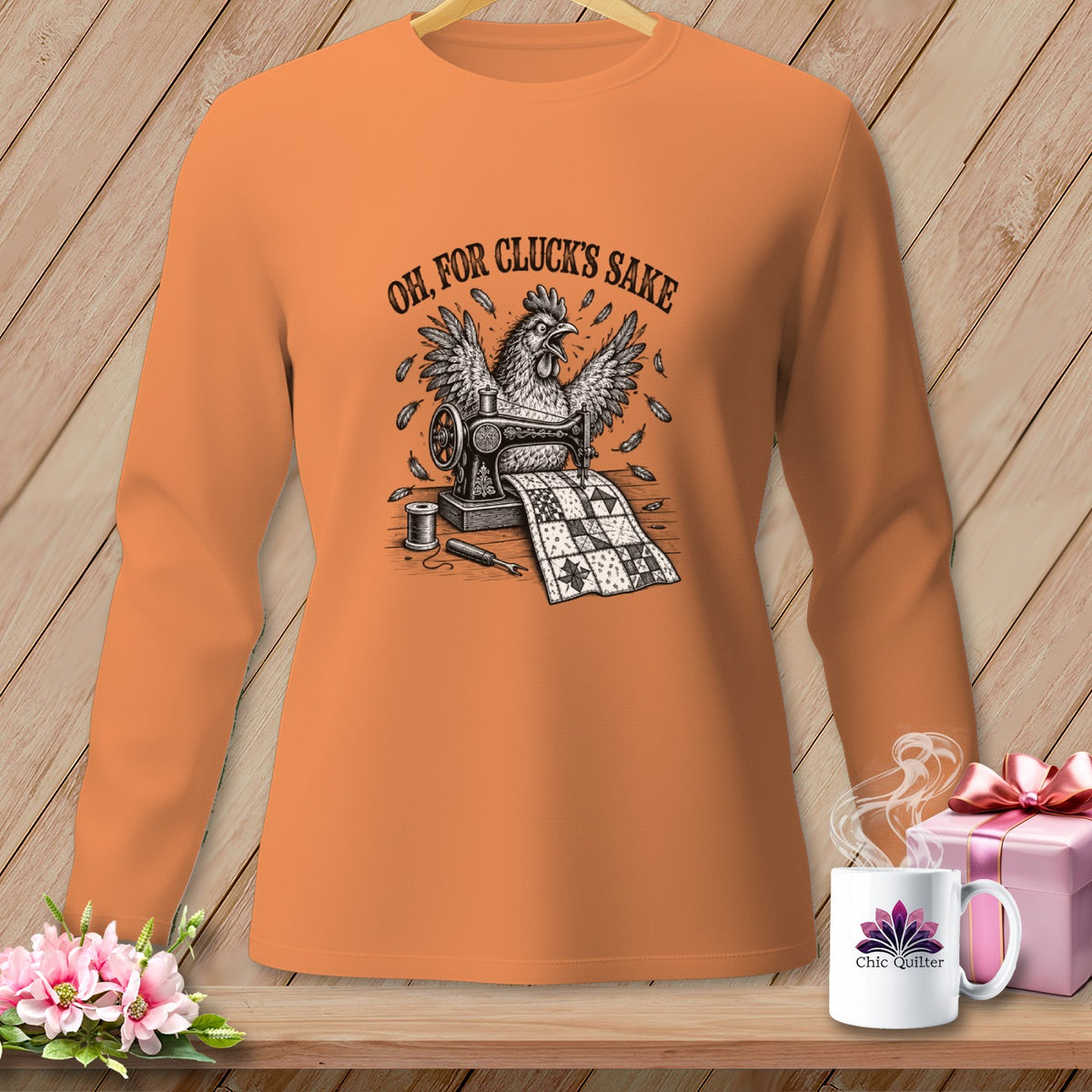 Orange long sleeve shirt with a chicken sewing a quilt and the text "OH, FOR CLUCK'S SAKE".