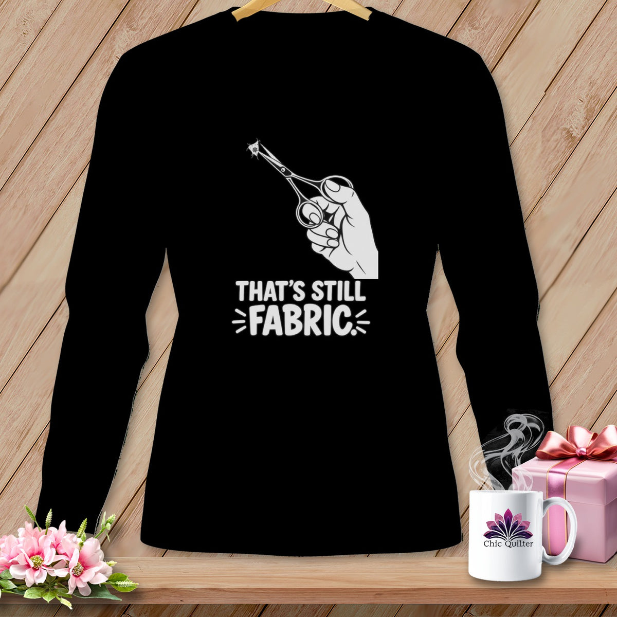 Black shirt with white graphic of scissors cutting fabric and text "That's still fabric".