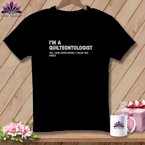 Black t-shirt with white text "I'm a Quilteontologist. Yes, I need coffee before I thread this needle."